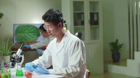 Asian Scientist Man Taking Genetic Solution From Test Tube With Micropipette Putting In Petri Dish Analyzing Medical Expertise. Biologist Researcher Working In Pharmaceutical Laboratory
