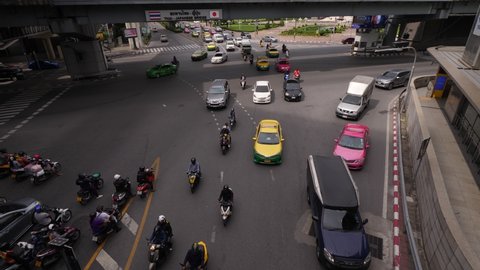BANGKOK - MAY 04, 2018: Cars and motorbike traffic flow at ground level of Sala Daeng intersection, tilt down shot from height. Thai - Japanese Flyover and corner of Lumphini park on background
