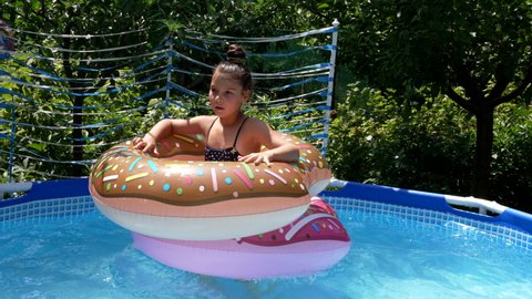 Happy girl child have fun floating in donut pool floats on sunny summer day, buoyancy