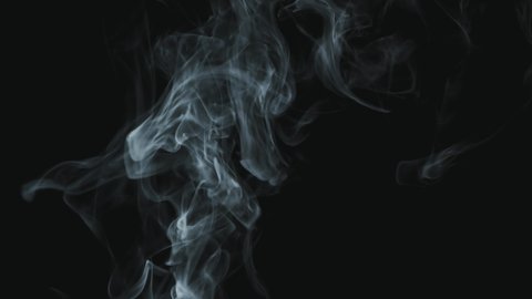 Close up of wisps of smoke rising upwards and flowing in slowmo isolated on black background