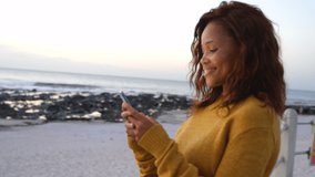 Smiling african american woman using smartphone at beach. communication technology and keeping in touch, digitally generated video.
