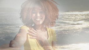 Animation of happy african american woman at beach over sun reflecting on sea. happy holidays and free time, digitally generated video.
