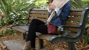 Animation of smiling asian woman in hijab using smartphone over park. global business, communication and keeping in touch digitally generated video.