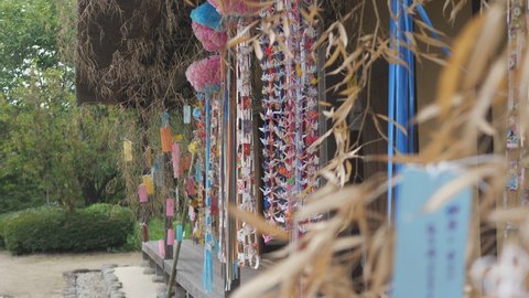 Tanabata decoration on the porch of old folk house. A strip of paper with a wish, thousand paper cranes, dried bamboo leaves. Traditional culture. Written in the Japanese "May every day be good life."