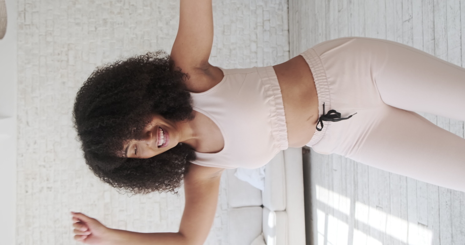 Trendy happy black mixed race woman vlogger listeng music, dances and recording videostream video for social media at home. Creating dancing video using tiktok app. Vertical video. | Shutterstock HD Video #1076719175