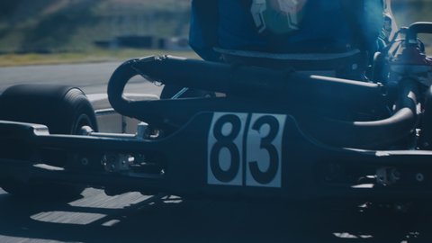 TRACKING Back view of teenager professional racer driving his go kart on a race track. Shot with 2x anamorphic lens