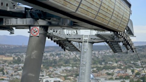 Riding modern aerial railway with sign Dont smoke on pole
