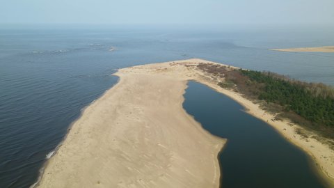 Aerial side shot of Mikoszewskie lake and Vistula River ended in sandbank of Mewia Lacha Nature Reserve during a sunny day, Baltic Sea Poland