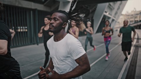 African American man and his like-minded friends dressed in a portable uniform have a group running training. Black man and his team of athletes running through the stadium.