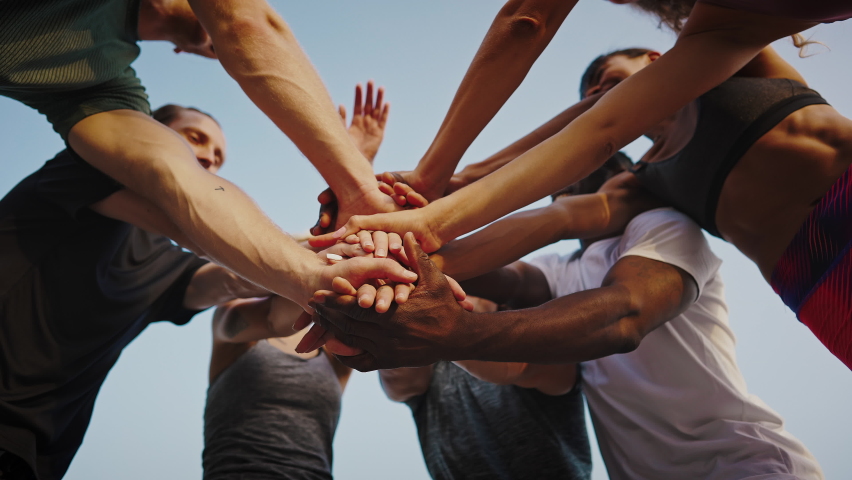Young beautiful group of sportswomen standing shaking hands after after a successful workout. A team of athletes, men and women, stand in a circle and shake hands. Group of like-minded people. Royalty-Free Stock Footage #1076730248