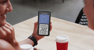 Man at cafe showing smartphone with covid vaccination certificate, eu flag and qr code on screen. healthcare, lifestyle, travel and technology during covid 19 concept digitally generated video.