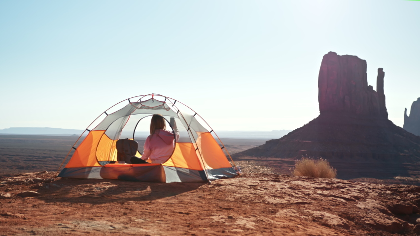 Camping woman in tent taking photo of cinematic nature landscape in Monument Valley with smart phone. Traveler using smartphone outdoors sharing travel adventure friends, enjoying Vacation USA 4K shot Royalty-Free Stock Footage #1076734391