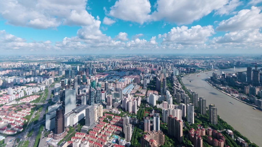 Time lapse of shanghai city in cloudy afternoon, aerial view of Shanghai skyline, ships sailing on Huangpu river, busy traffic on road, clouds moving and shadows follow, 4k footage, tilt up shot.
