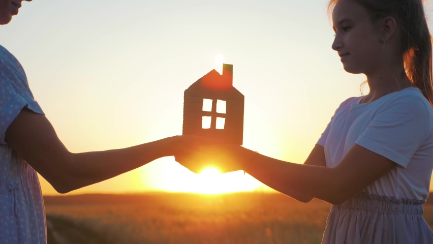 Silhouette happy mother and daughter with dream house. Paper house as a symbol. The concept of family happiness.