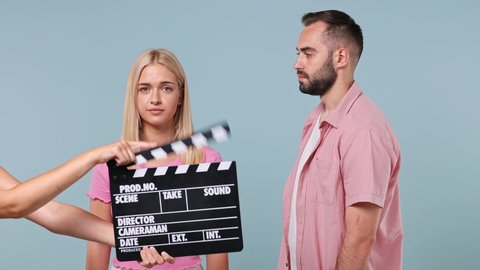 Young couple two actors family man woman in pink clothes start play emotion like movie theater after clapperboard gesture fainting begging isolated on pastel plain light blue color background studio