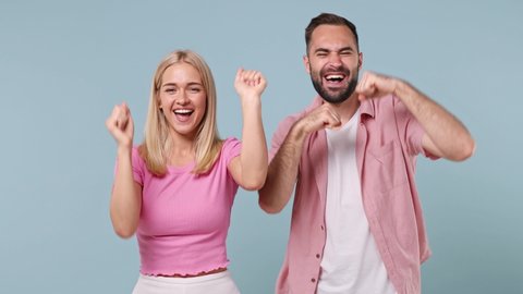 Young couple two friends family man woman in pink clothes together dancing have fun expressive gesticulate hands show victory sign isolated on pastel plain light blue color background studio portrait