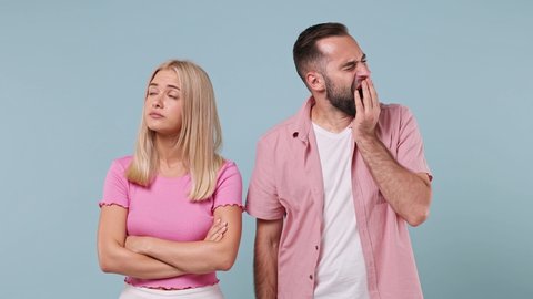 Boring young couple two friends family man woman in pink clothes together look aside did not get enough sleep last night yawning isolated on pastel plain light blue color background studio portrait