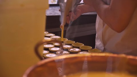 pastry chef behind the counter makes and fills traditional Portuguese pastel de nata pastries with custard