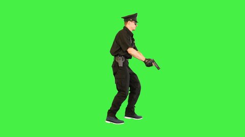 Policeman in uniform runs aiming with a gun on a Green Screen, Chroma Key.