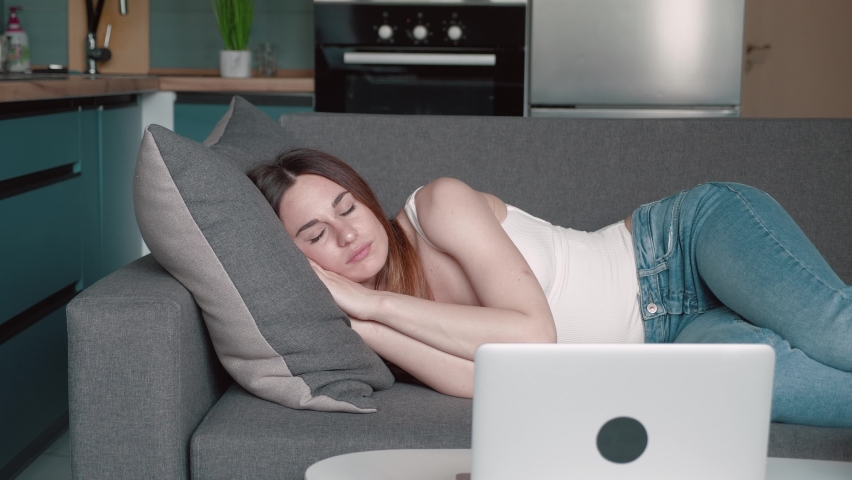 Apathetic young sleepy woman falls down on sofa. Exhausted tired lazy lady sleeping on couch at home alone. Funny girl lying asleep feeling lack of motivation, fatigue or depression concept | Shutterstock HD Video #1076763800
