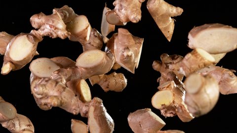 Super slow motion of cut ginger roots flying in the air on black background. Filmed on high speed cinema camera.