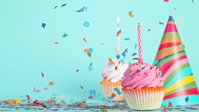Falling Colorful Confetti with Birthday Cap and Cupcakes on Pastel Blue Background. Super Slow Motion. - Powered by Shutterstock - Get 15% off with code: PIKWIZARD15