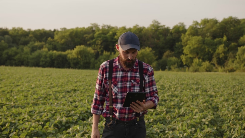 Happy handsome farmer with beard shows friends his bautiful fields