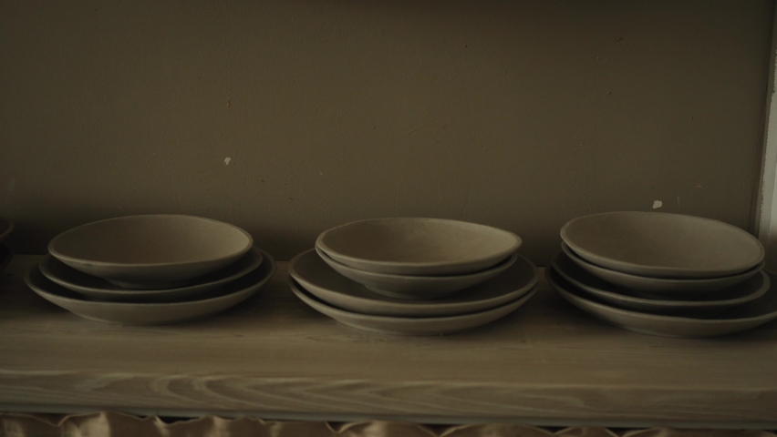 Shelves with ceramic dishware in pottery workshop | Shutterstock HD Video #1076779157