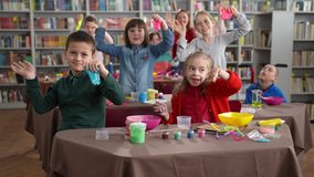 Joyful children with special needs waving hands while posing on camera with self-made slimes after inclusive masterclass. Cheerful disabled and healthy kids with female teacher posing for video shot - Powered by Shutterstock - Get 15% off with code: PIKWIZARD15