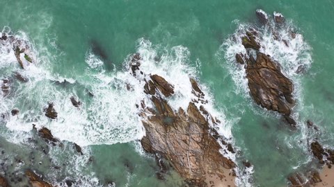 aerial top view waves crashing on the rock beside the beach.
white bubble waves in turquoise sea on the rock. 
creative nature and travel concept. 
