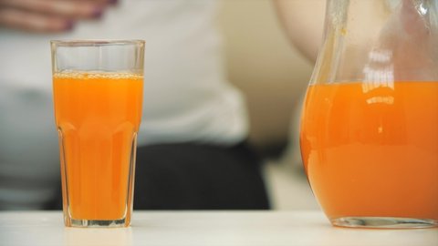 4k slowmotion video of female hand taking a glass of orange juice.