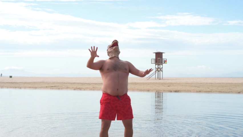 Man with lost lizard mask on shore of beach during sunny day