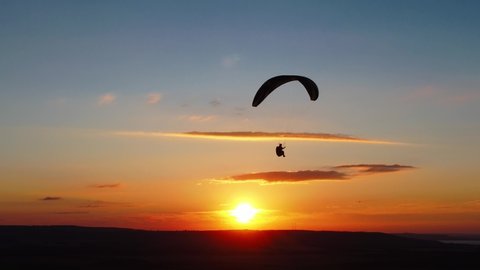 silhouette paraglider flying against colorful sunset sky. extreme sports, paragliding. recreational adventure sport.