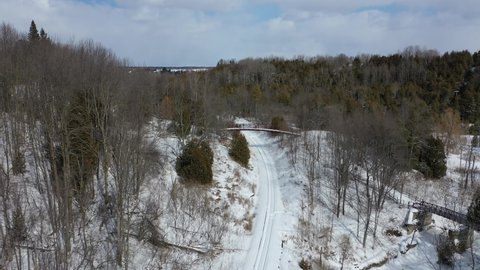 Aerial view of snowy railroad train line through winter forest
