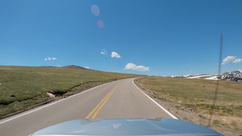 POV Driving a car going up on curvy asphalt road in Montana mountains. Areas of snow on the hill slopes
