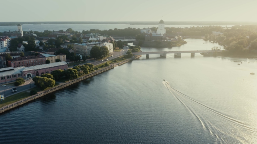 Aerial shot of the city of Vyborg, the Vyborg Castle and mooving motorboat at sunset, Russia