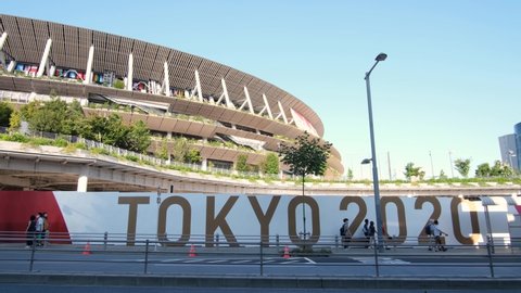 Shinjuku, Tokyo, Japan - July 31, 2021: People walk near Tokyo 2020 sign and the Japan National Stadium (Olympic Stadium), stadium of summer olympic games 2020 2021 in Japan 