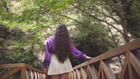 Girl With Short White Dress and Violet Top Walking on Wooden Bridge in a Garden in Slow Motion