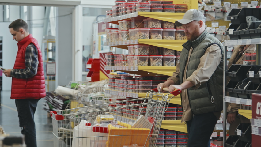Slowmo PAN of couple with shopping cart walking through busy hardware store