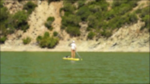 Blurred background and in the background a woman doing Paddle Surf in the Bornos reservoir in Cádiz. Spain. Outdoor sports.