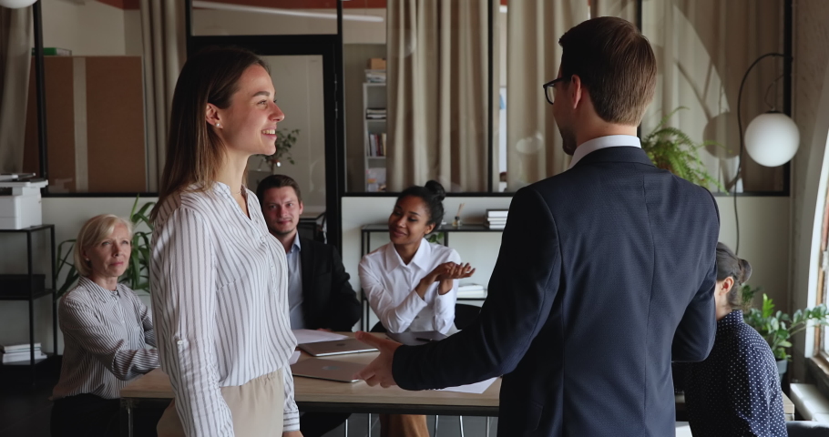 Company leader shake hands young associate, praising for work, thank for good job done at briefing with diverse employees clap hands congratulating teammate. Encouraging best employee of month concept Royalty-Free Stock Footage #1076855789