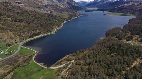 Aerial drone footage of Lake Sils in the Engadin valley in the alps in Canton Graubunden in Switzerland on a sunny summer day. Shot with a tilt up revealing motion. 