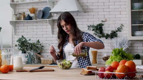 Woman pouring oil in vegetable salad. Female chef pouring olive oil in salad. Beautiful woman cooking salad in bowl. Woman dressing fresh salad with olive oil. Healthy breakfast. Vegan lifestyle