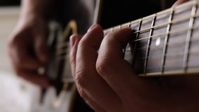 Playing the guitar. Strumming acoustic guitar. Musician plays music. Man fingers holding mediator. Man hand playing guitar neck in dark room. Unrecognizable person rehearsing, fretboard close-up. - Powered by Shutterstock - Get 15% off with code: PIKWIZARD15