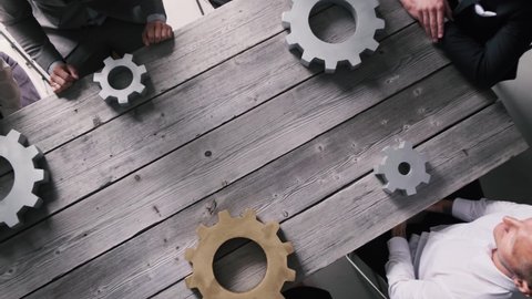 Teamwork business people concept. Different hands of men and women connect gears into working mechanism on wooden table background.