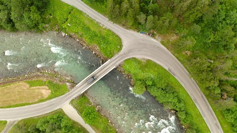 Vehicle Passes On Small Bridge Over Watercourse In Geiranger, Norway. aerial top-down