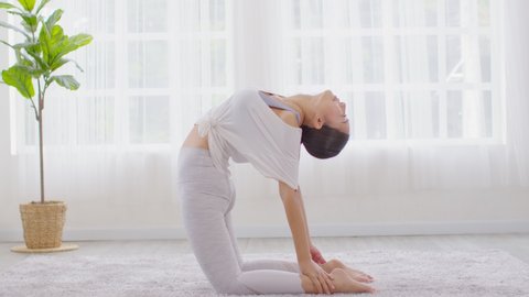 Attractive Asian woman practice yoga Ustrasana pose or yoga Camel pose deep breath to meditation in bedroom after wake up in the morning Feeling so comfortable and relax,Yoga for Healthcare Concept