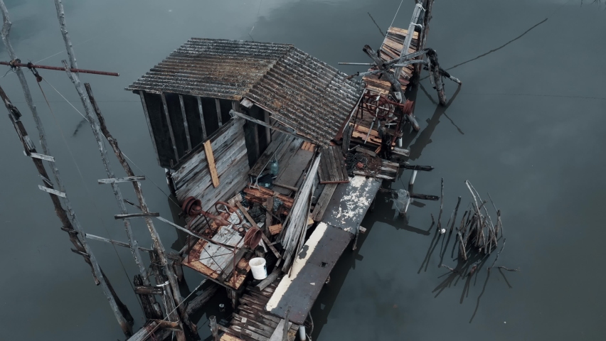 Aerial view of an old abandoned fishing shack in the Buna river in Ulcinj Montenegro Europe during summer season fish net cold water drone wet wood metal asbestos 