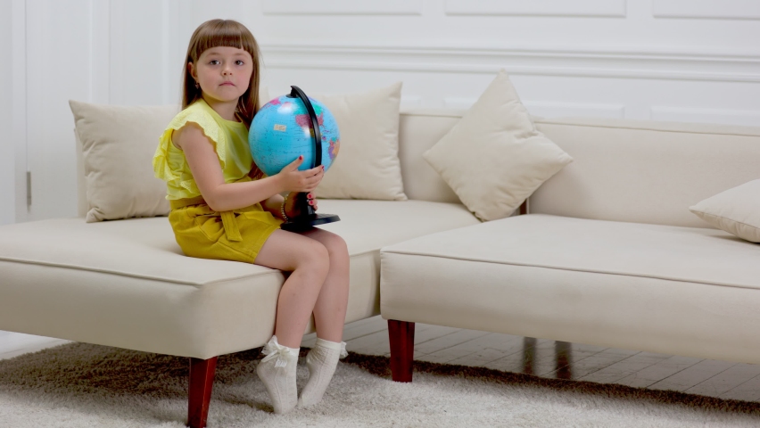 child looking at the globe sitting on the couch