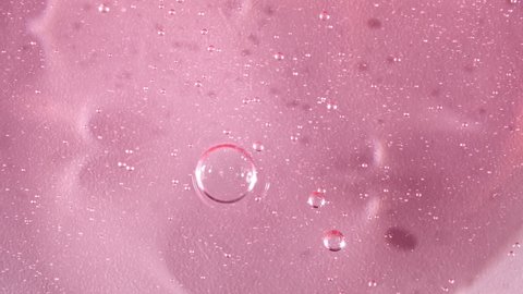 Red Transparent Cosmetic Gel Cream With Molecule Bubbles Flowing On The Plain White Surface. Macro Shot